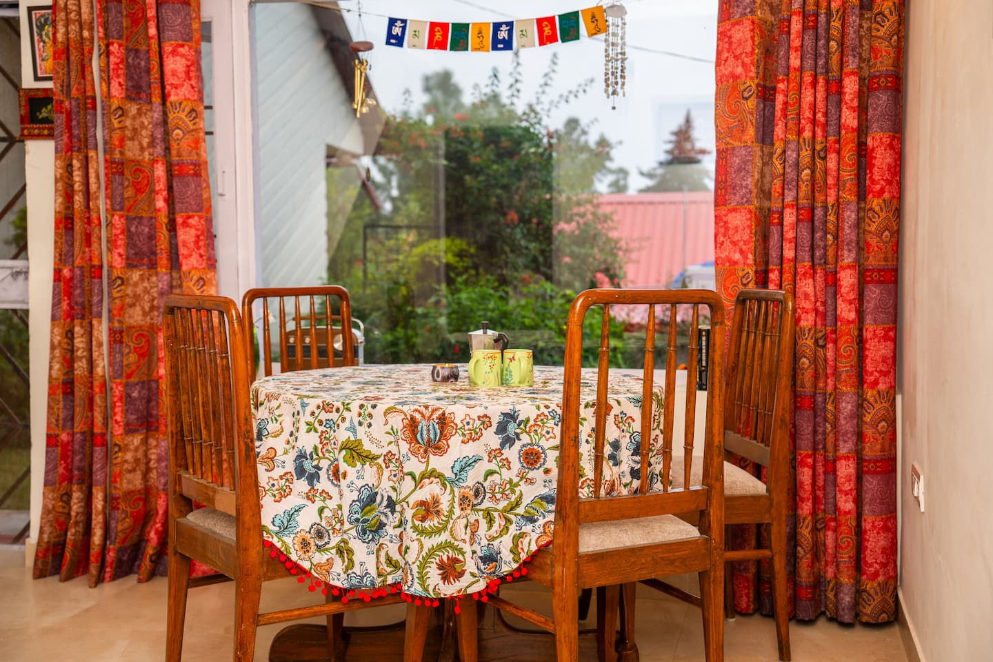Dining table by the window with prayer flags and printed curtains