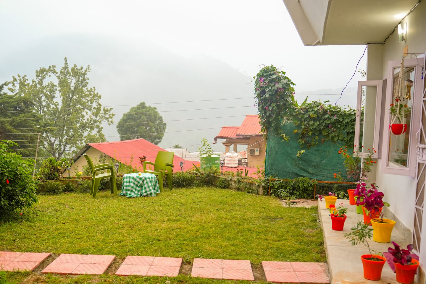 Green lawn and flower pots with the misty hills behind the house